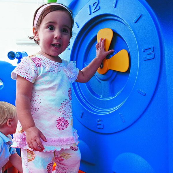 discovery center toddler play systems girl playing with the clock panel